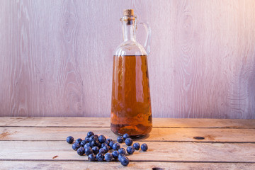 pacharán bottle on wooden table beside sloes
