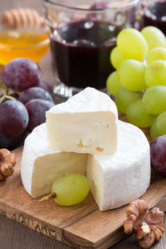 fresh camembert on a wooden board and grapes, vertical