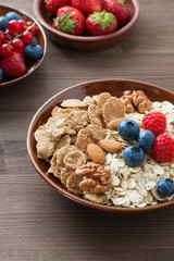 oatmeal and muesli in a bowl, fresh berries on wooden background