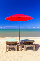 Red parasol with deckchair on tropical beach in Thailand