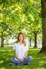 Fototapeta premium Pretty redhead smiling at camera in the park