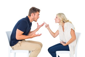 Young couple sitting in chairs arguing