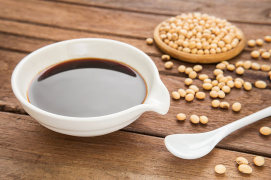 Soy sauce and soy bean on wooden background