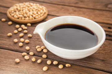 Soy sauce and soy bean on wooden background