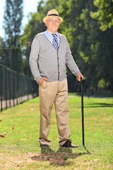Senior with cane posing in a park