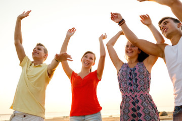 smiling friends dancing on summer beach