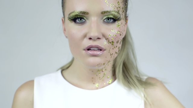 Sexy woman in artistic golden make-up posing in studio.