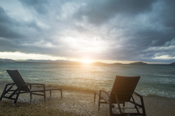 two sun loungers against sea and clouds
