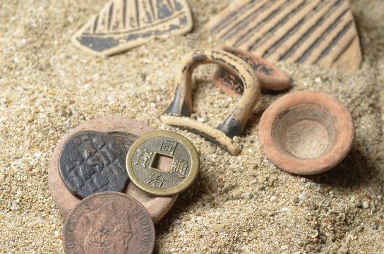 pezzi di vasi antichi su sabbia con monete antiche
