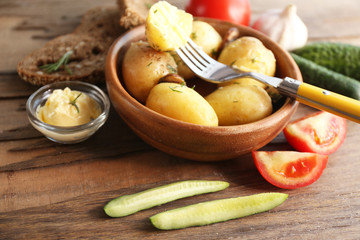 Young boiled potatoes in bowl on wooden table, close up