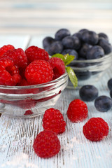 Glass bowls of raspberries and blueberries