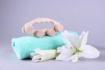 Wooden roller brush, towels and lily on grey background
