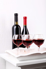 Glasses and wine bottle on tray in room