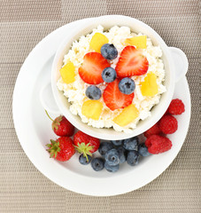 Cottage cheese with fruits and berries in bowl on table