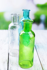 Empty glass bottles on table on bright background