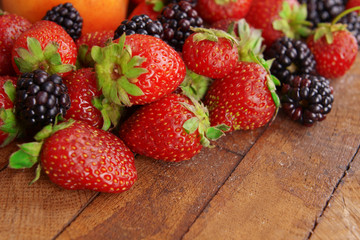 Blackberries and strawberries on wooden background