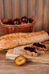 Bread with plum jam on wooden table close-up