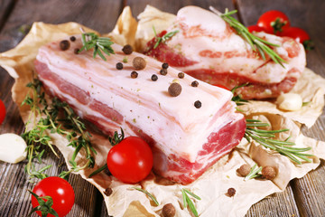 raw bacon with spices and tomatoes on wooden table