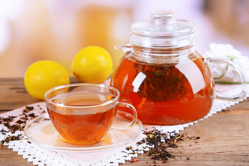 Teapot and cup of tea on table on light background