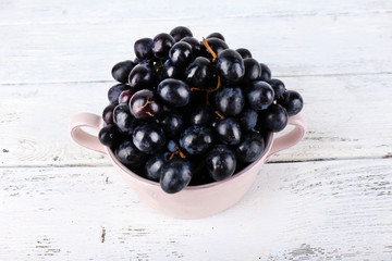 Purple grapes in bowl on wooden background