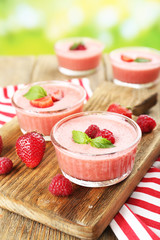 Delicious berry mousse in bowls on table on bright background