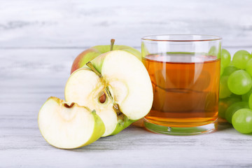 glass of juice with fresh grape and apples on grey wooden table
