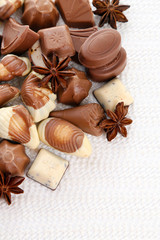 Different kinds of chocolates with spices on white background