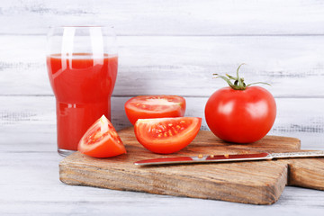 glass of tasty tomato juice and fresh tomatoes on wooden table
