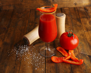glass of tasty tomato juice and pepper on wooden table