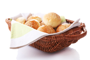 Tasty buns with sesame in wicker basket, isolated on white