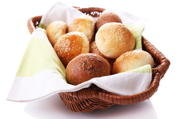 Tasty buns with sesame in wicker basket, isolated on white
