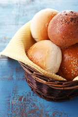 Tasty buns with sesame in wicker basket,