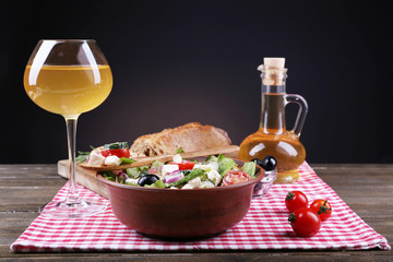 Bowl of Greek salad served with olive oil and glass of wine