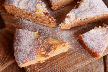 Pieces of delicious cake on cutting board on wooden table