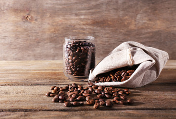 Coffee beans in fabric bag and glass jar on wooden background