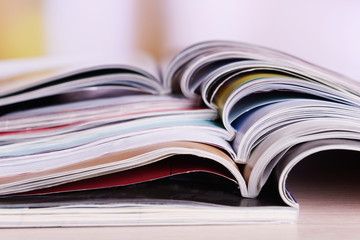Magazines on wooden table on bright background