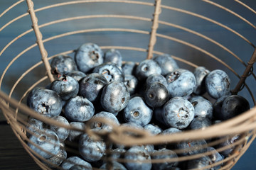 Tasty ripe blueberries in metal basket, on wooden background