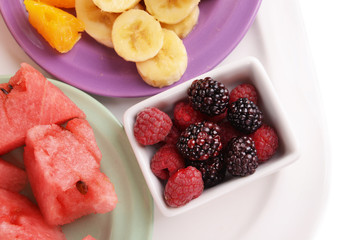 Slices of fruits with berries on plate close up