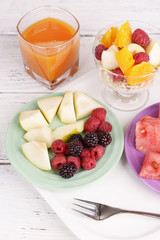 Slices of fruits with berries and muesli on wooden table