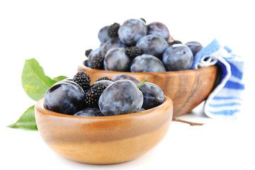Ripe sweet plums in wooden bowls, isolated on white