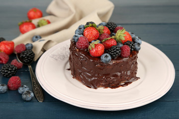 Tasty chocolate cake with different berries, on wooden table