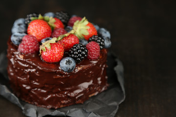 Tasty chocolate cake with different berries on wooden table