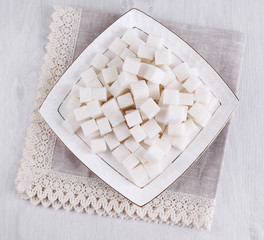 Refined sugar on plate on wooden background