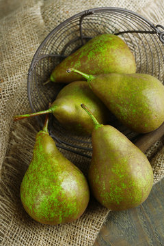 Ripe pears in basket on wooden background