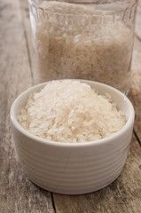 Rice in bowl on wooden background close up