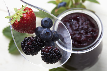 Waldfruchtmarmelade, Plastiklöffel, weisser Holzuntergrund