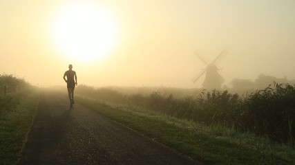 Young man running at foggy sunrise.
