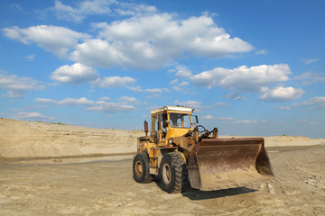 Sand quarry, excavating equipment, bulldozer with heap of sand