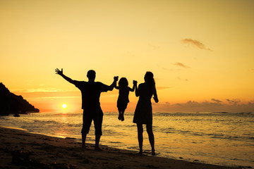 Happy family playing at the beach in the dawn time