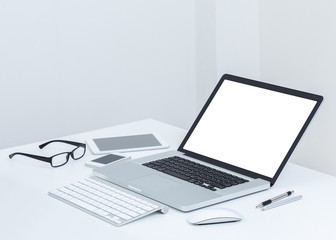 Blank screen laptop computer with accessories on white table